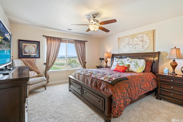 bedroom with a textured ceiling, light colored carpet, and ceiling fan