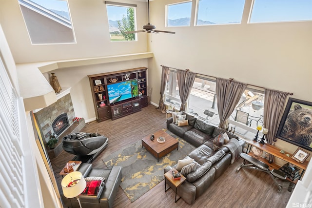 living room featuring wood-type flooring, ceiling fan, and a fireplace