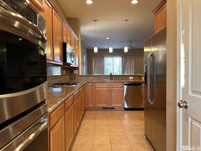 kitchen featuring appliances with stainless steel finishes, sink, kitchen peninsula, pendant lighting, and backsplash