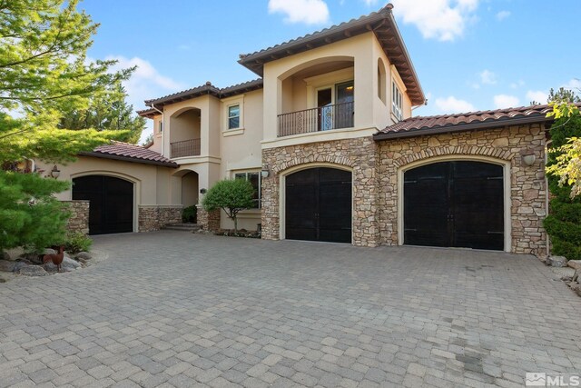 mediterranean / spanish-style house featuring a garage and a balcony