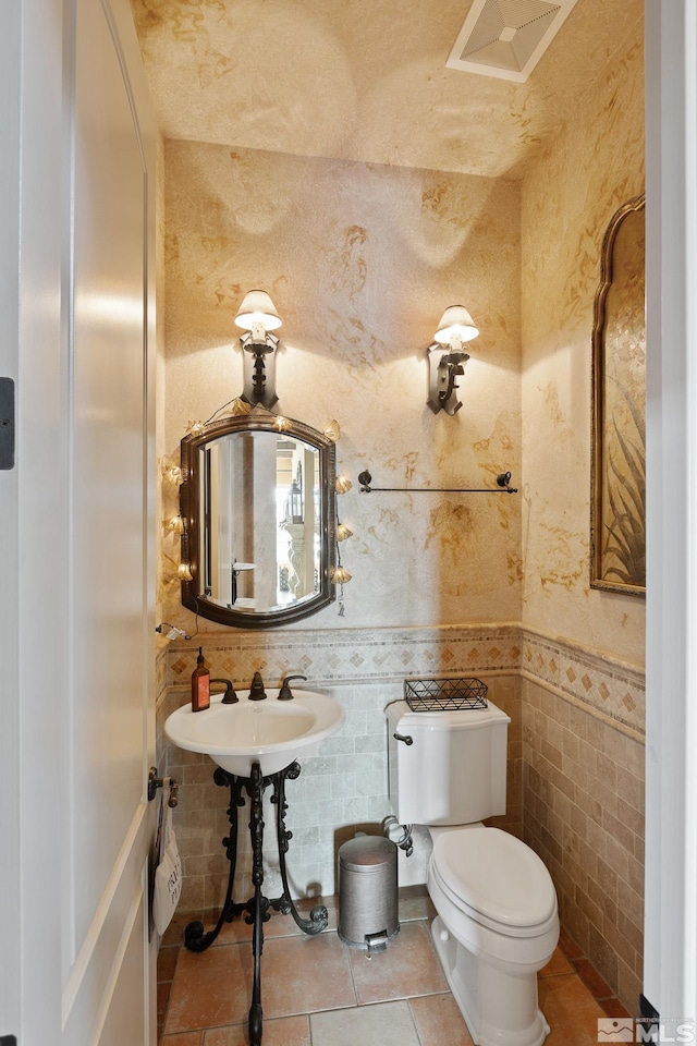 bathroom with tile patterned flooring, tile walls, and toilet