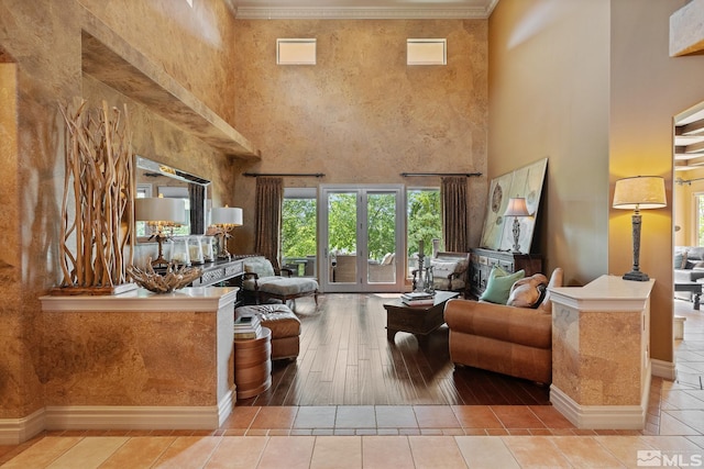 living room with crown molding, french doors, light hardwood / wood-style floors, and a towering ceiling