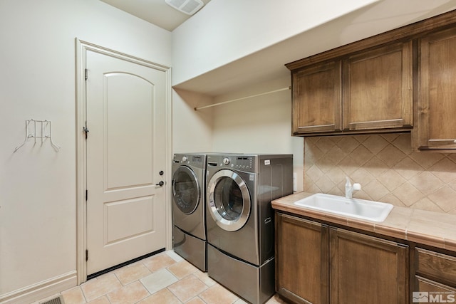 clothes washing area with cabinets, separate washer and dryer, light tile patterned floors, and sink