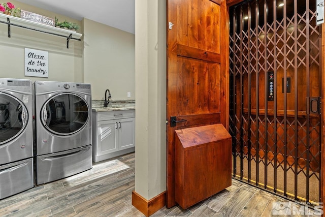 laundry area with sink, cabinets, washing machine and clothes dryer, and light wood-type flooring