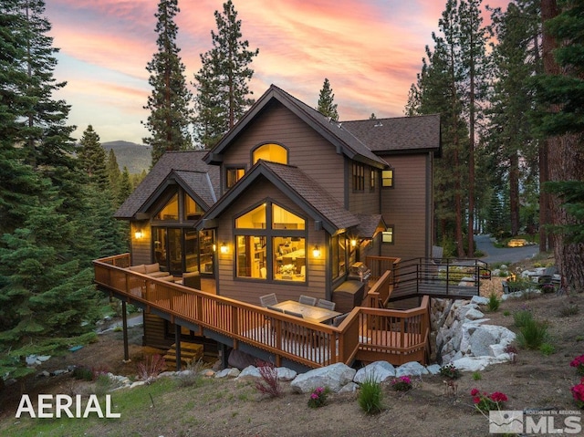 back house at dusk with a wooden deck