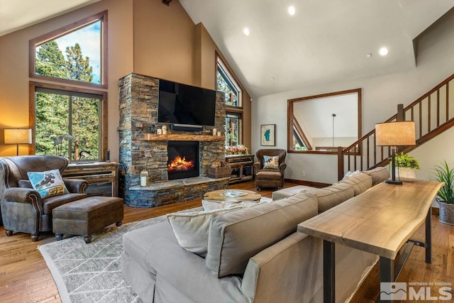 living room featuring hardwood / wood-style flooring, plenty of natural light, a fireplace, and high vaulted ceiling