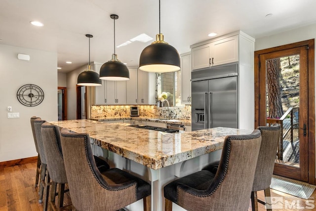 kitchen featuring hanging light fixtures, light stone countertops, appliances with stainless steel finishes, and backsplash