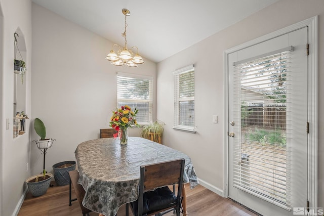 dining space featuring vaulted ceiling, a notable chandelier, light wood-type flooring, and plenty of natural light