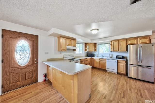 kitchen with kitchen peninsula, light hardwood / wood-style flooring, stainless steel appliances, and a textured ceiling