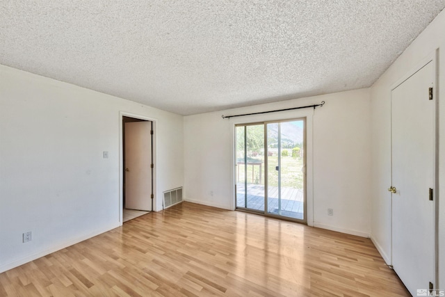 unfurnished room with light hardwood / wood-style flooring and a textured ceiling