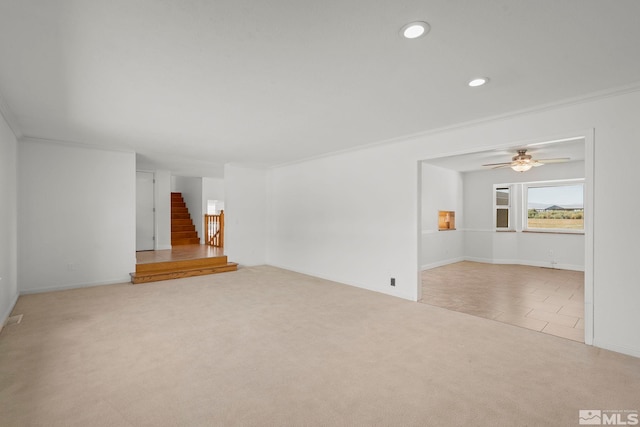 unfurnished living room featuring ornamental molding, ceiling fan, and light colored carpet