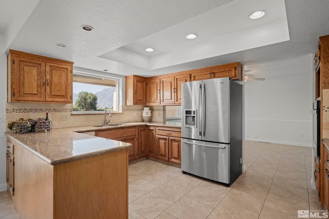 kitchen featuring backsplash, light tile patterned floors, sink, stainless steel fridge, and ceiling fan