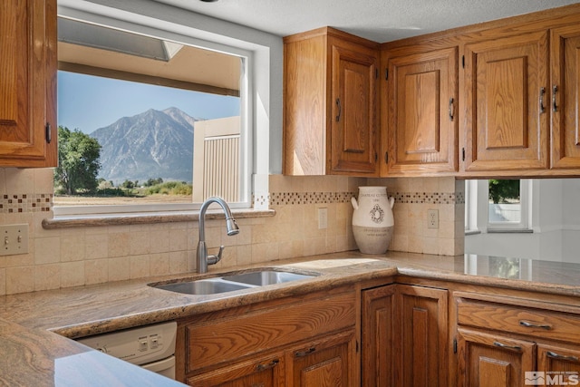 kitchen featuring a textured ceiling, a mountain view, sink, decorative backsplash, and washer / clothes dryer