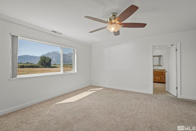 unfurnished room with crown molding, light colored carpet, a mountain view, and ceiling fan