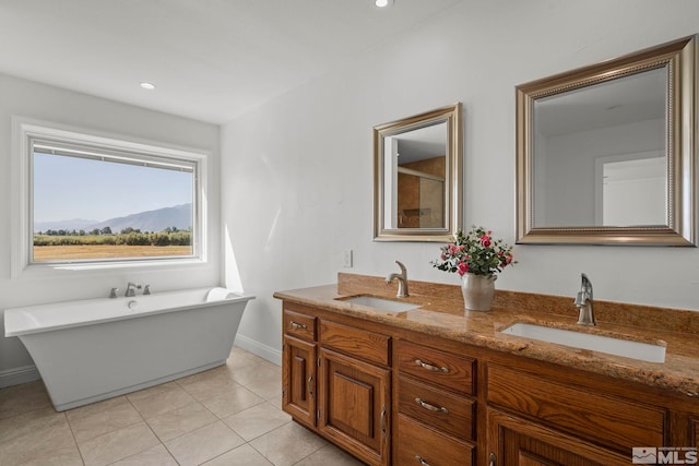 bathroom with a bath, tile patterned flooring, a mountain view, and vanity