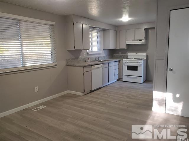 kitchen with light countertops, light wood-style flooring, white cabinets, white appliances, and under cabinet range hood