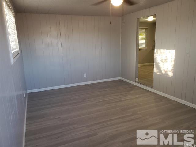 spare room with a ceiling fan, baseboards, and dark wood-type flooring