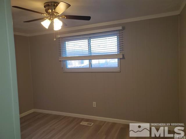 unfurnished room with baseboards, visible vents, a ceiling fan, ornamental molding, and wood finished floors