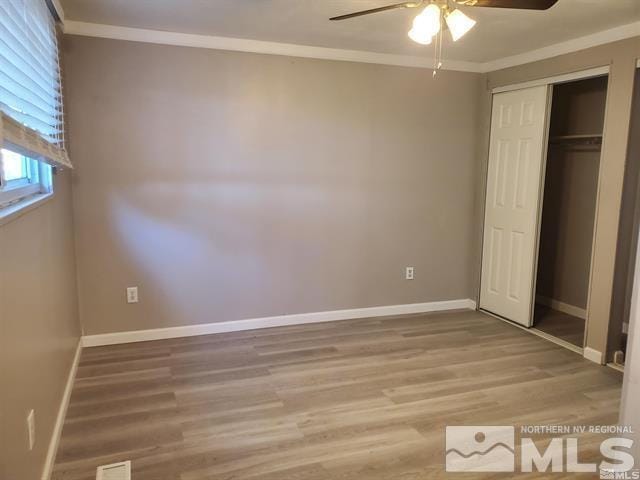 unfurnished bedroom featuring baseboards, crown molding, and wood finished floors