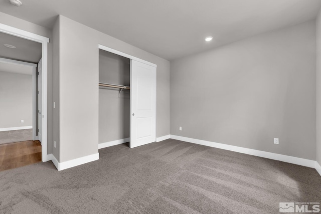 unfurnished bedroom featuring a closet and dark colored carpet