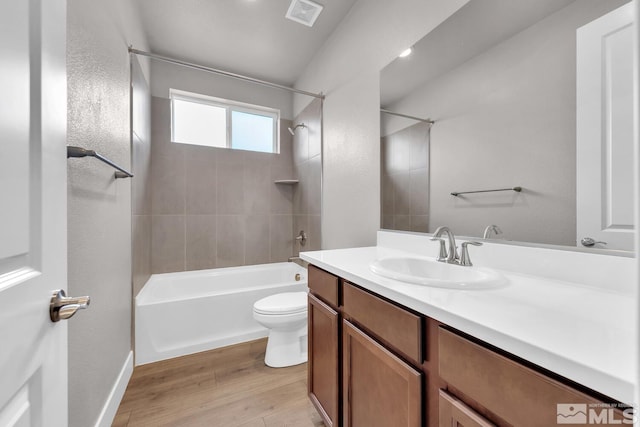 full bathroom with tiled shower / bath, vanity, toilet, and hardwood / wood-style floors