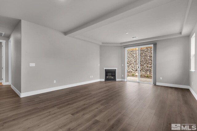 unfurnished living room with hardwood / wood-style floors and a tray ceiling