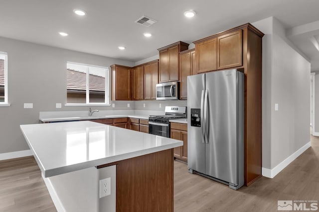 kitchen with sink, stainless steel appliances, light hardwood / wood-style floors, and a kitchen island