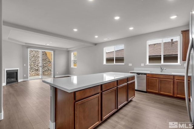 kitchen with stainless steel dishwasher, light hardwood / wood-style floors, sink, and a kitchen island