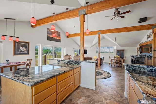 kitchen featuring beamed ceiling, hanging light fixtures, a kitchen island, tile patterned floors, and dark stone countertops