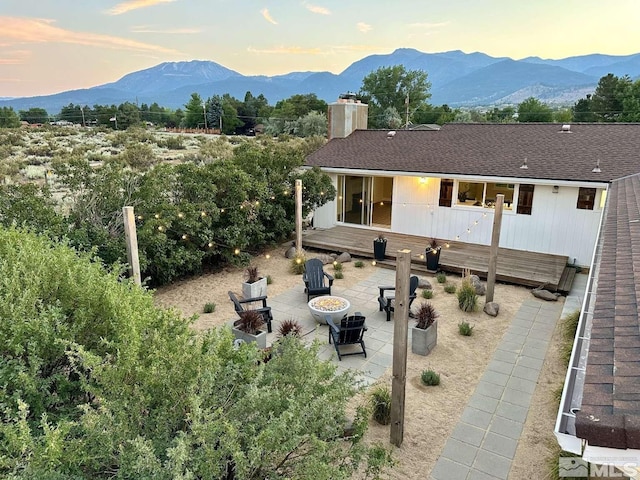 back house at dusk featuring an outdoor fire pit, a patio area, and a deck with mountain view