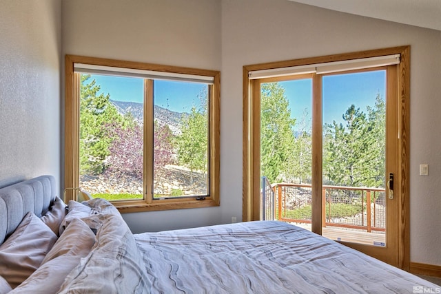 bedroom featuring lofted ceiling, a mountain view, and multiple windows