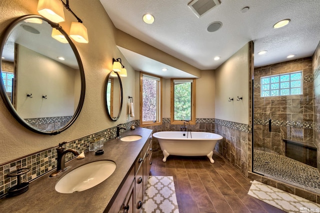 bathroom with shower with separate bathtub, tile walls, a textured ceiling, vanity, and hardwood / wood-style flooring