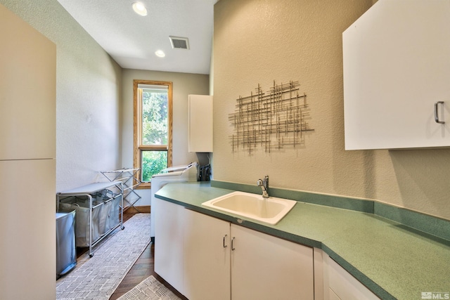 kitchen with white cabinetry, dark hardwood / wood-style floors, washer / clothes dryer, and sink