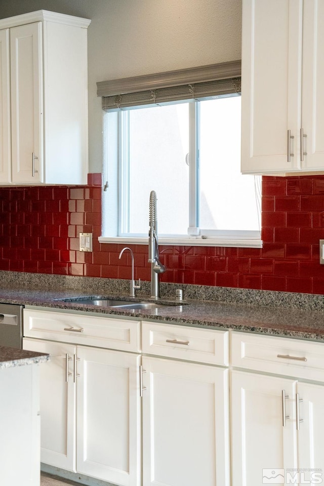 kitchen with white cabinetry, dark stone countertops, and backsplash