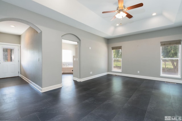 unfurnished room featuring a raised ceiling and ceiling fan