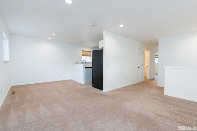 unfurnished living room featuring sink and light carpet