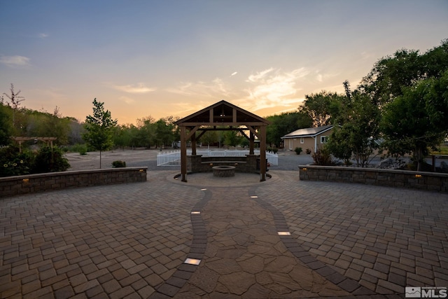 patio terrace at dusk featuring a gazebo and a fire pit