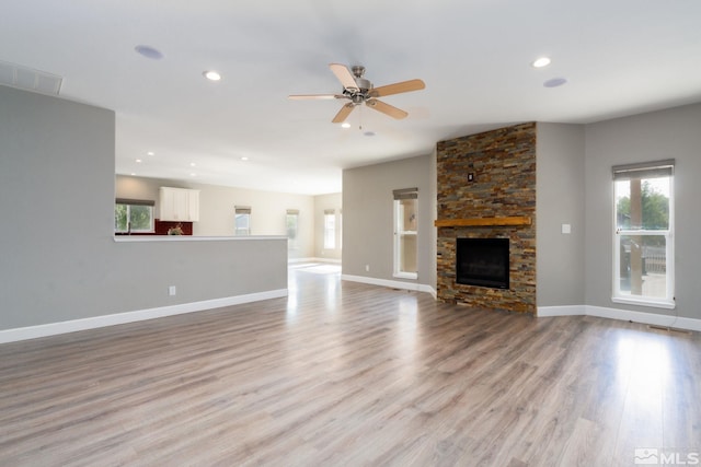 unfurnished living room featuring ceiling fan, a fireplace, and light wood-type flooring