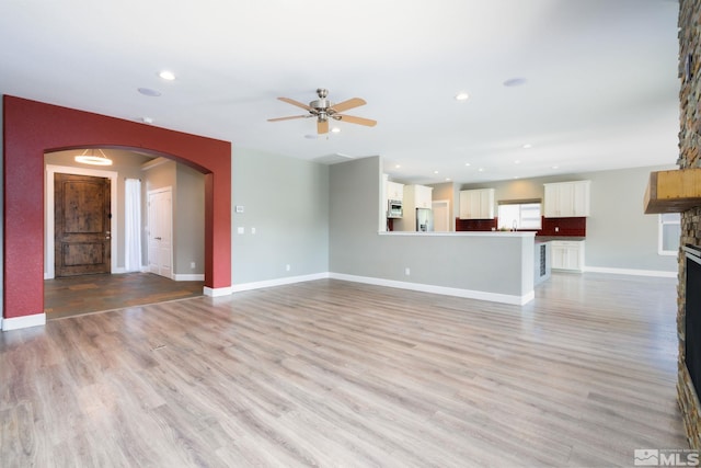 unfurnished living room featuring a fireplace, light hardwood / wood-style flooring, and ceiling fan