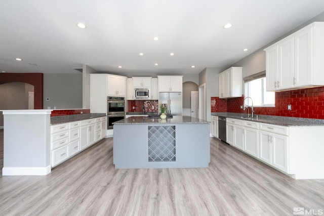 kitchen featuring sink, light hardwood / wood-style flooring, appliances with stainless steel finishes, white cabinets, and a kitchen island