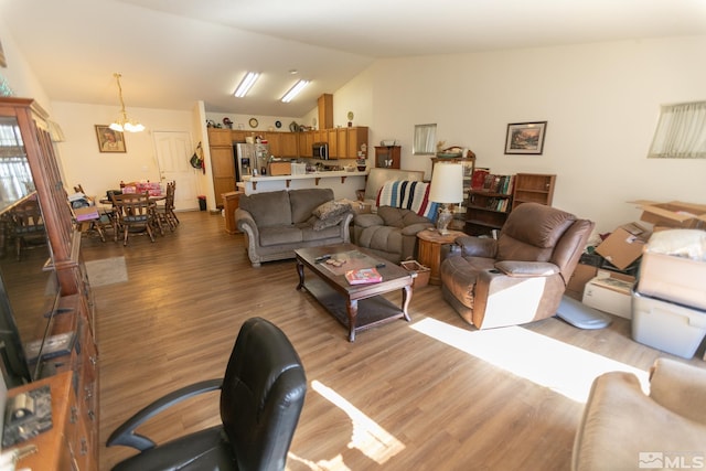 living room with an inviting chandelier, lofted ceiling, and light wood-type flooring