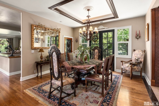 dining space with hardwood / wood-style flooring, a notable chandelier, and a tray ceiling