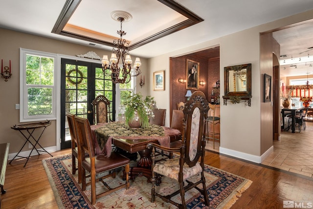 dining area featuring a notable chandelier, light hardwood / wood-style floors, and a tray ceiling