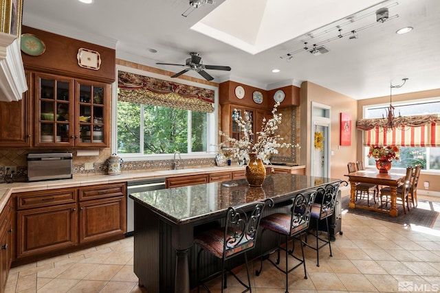 kitchen featuring sink, a breakfast bar, dark stone countertops, a center island, and stainless steel dishwasher