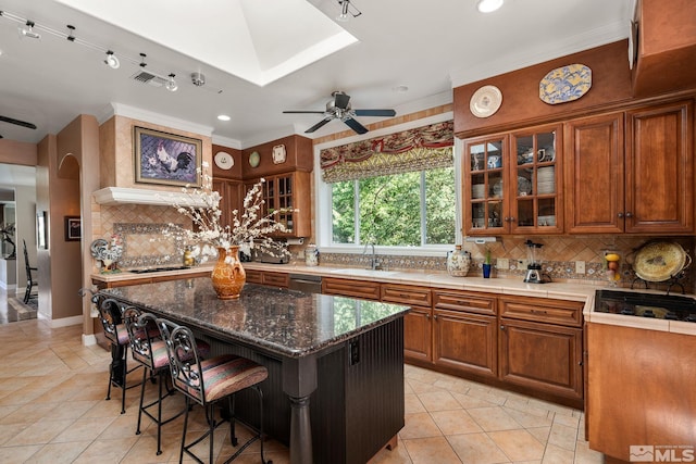 kitchen featuring a center island, dark stone countertops, a kitchen breakfast bar, dishwashing machine, and backsplash