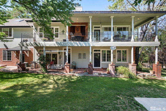 rear view of house featuring a balcony and a yard