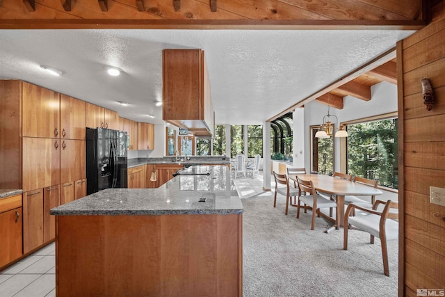 kitchen with a textured ceiling, dark stone counters, black refrigerator with ice dispenser, and light colored carpet