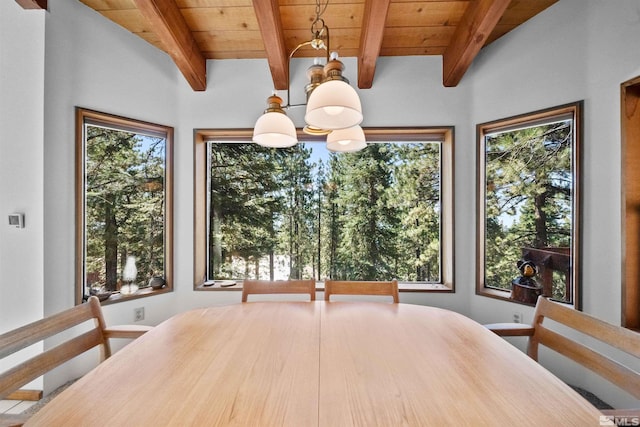 dining space with a notable chandelier, a wealth of natural light, and beam ceiling