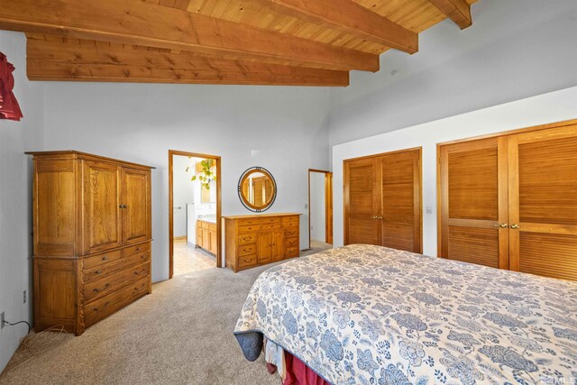 carpeted bedroom featuring lofted ceiling with beams, ensuite bath, and two closets