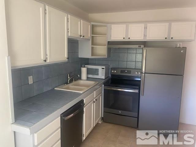 kitchen featuring appliances with stainless steel finishes, decorative backsplash, tile counters, and sink